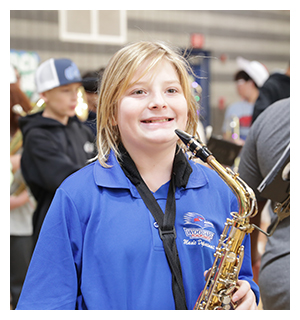 Student smiling with a saxophone